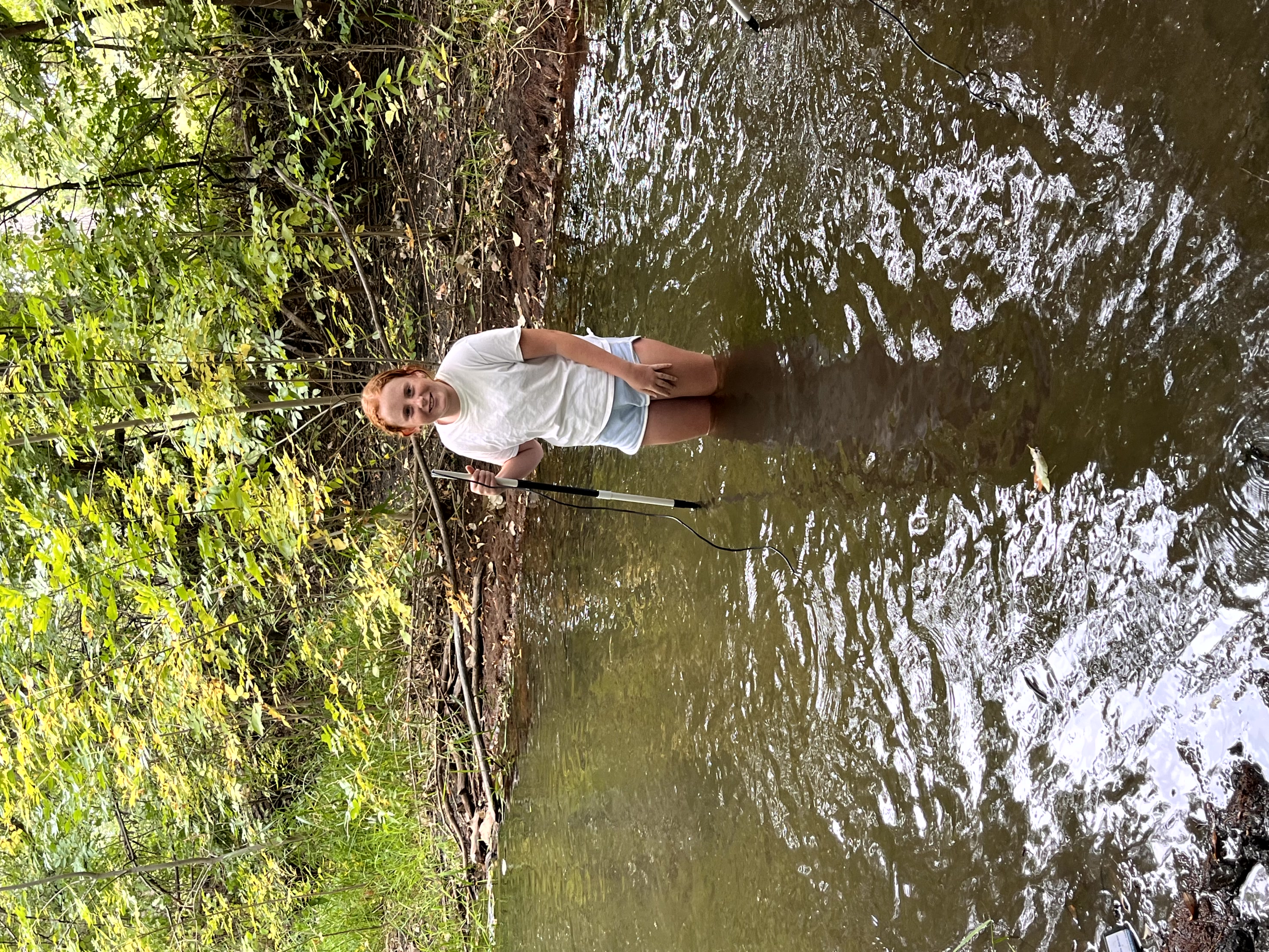 Student in the Poudre River with science probe